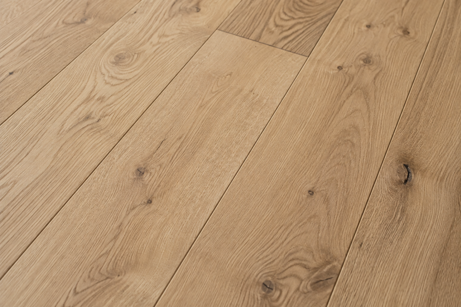 Gros plan sur un parquet en chêne brut, lattes de bois juxtaposées.