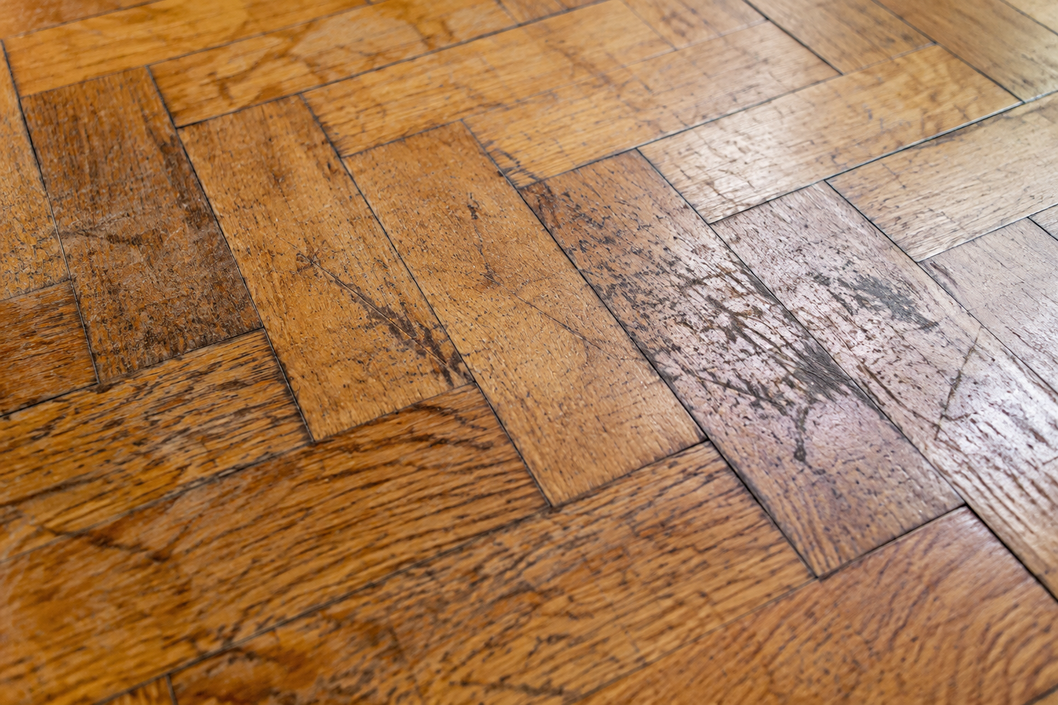 Gros plan sur un parquet présentant des rayures et de l'usure, avant ponçage
